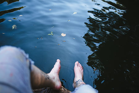 person wearing blue shorts sitting in front of body of water thumbnail