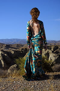 Woman Wearing Blue and Multicolored Floral Backless Long-sleeved Dress Standing in Front of Rock Formation thumbnail