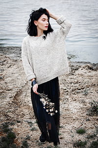 woman in gray sweater holding white flowers thumbnail
