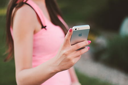 person in pink sleeveless top holding white iPhone 5 thumbnail