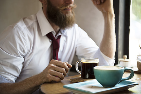 man sitting in front of table with coffee on top of it thumbnail