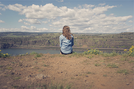 woman in blue shirt on top of cliff under stratus clouds thumbnail