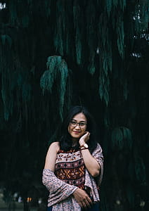Woman in Brown Floral Top Stands Beside Tree thumbnail