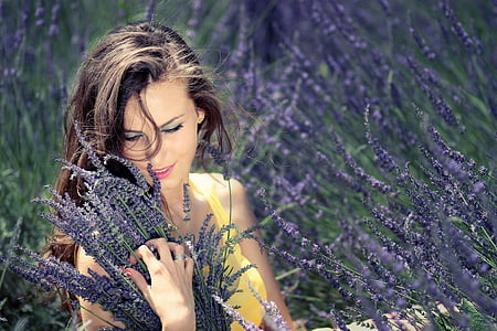 selective focus photograph of woman holding leaves thumbnail