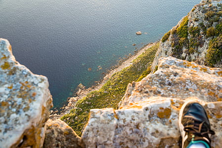 person standing on ledge overlooking sea thumbnail