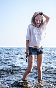 woman standing on boulders near body of water thumbnail