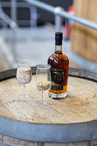 ktwo clear wine glasses beside glass bottle on top of barrel thumbnail