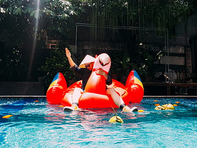 person riding red inflatable bird boat on swimming pool thumbnail