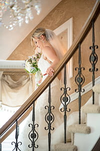 Woman Wearing Wedding Dress Holding Bouquet Walking Down Stairs thumbnail
