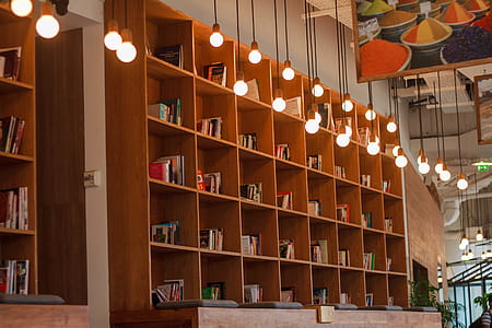 Books Inside Bookshelf Near Lit Pendant Lights thumbnail