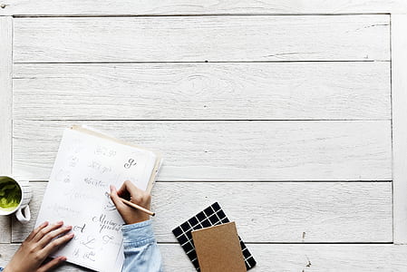 person holding pencil on white top of white paper thumbnail