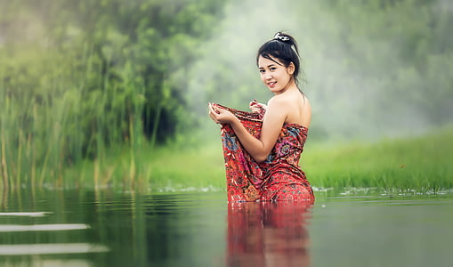 woman wearing red and multicolored tube dress stand on body of water thumbnail