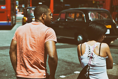 A couple wait to cross the road in a busy part of West London, buses and taxis can be seen in the background thumbnail
