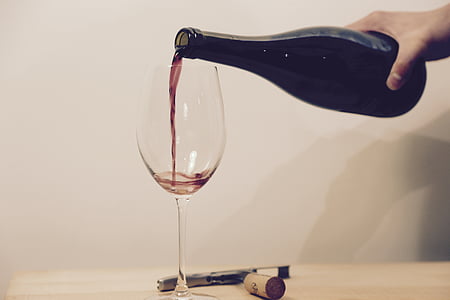 closeup photo of person holding liquor bottle near wine glass thumbnail
