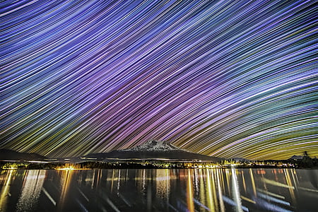 gray and white mountain near body of water during night time thumbnail