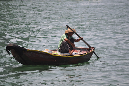 man boating on body of water and wearing brown straw hat during daytime thumbnail