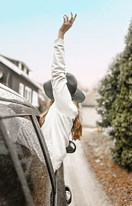 woman leaning outside of car through window raising her hand thumbnail