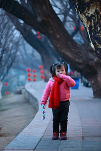selective focus photo of girl standing on green pathway near the brown tree thumbnail