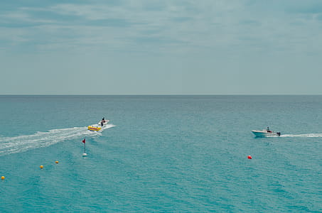 Two People Rides Watercrafts On Body Of Water Under Clear Blue Sky thumbnail