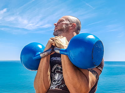 Man Lifting Pair of Blue Kettlebells thumbnail