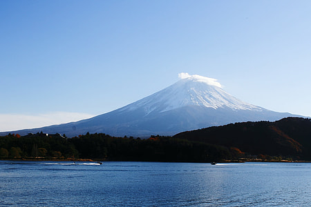 calm body of water near mountain and volcano under blue sky at daytime thumbnail