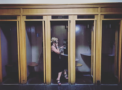 woman using telephone inside telephone booth thumbnail