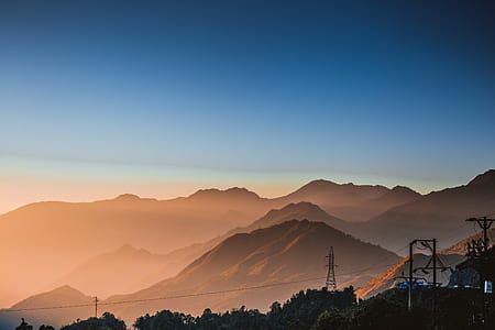 transmission tower near hills and tall trees thumbnail