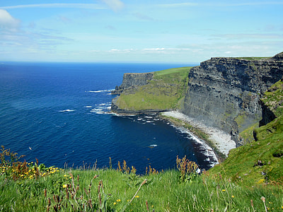 green filled mountain beside blue sea under blue sky thumbnail
