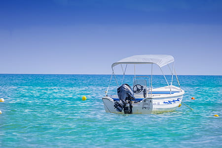 white and blue boat on blue water under blue sky thumbnail