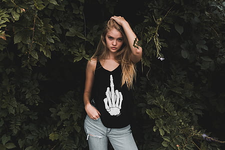 woman in black tank top standing behind green leaves thumbnail