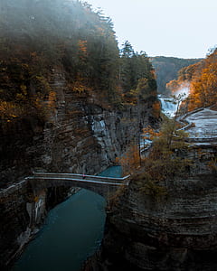 person walking on bridge connecting mountain at daytime thumbnail