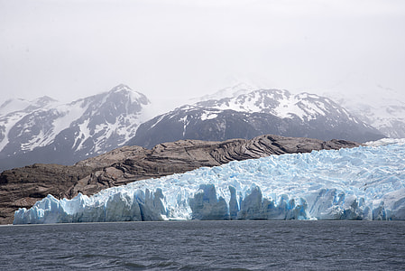 iceberg on body of water near snow mountains thumbnail
