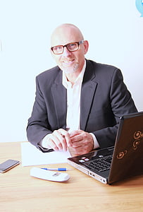 man wearing black suit jacket sitting by the table thumbnail