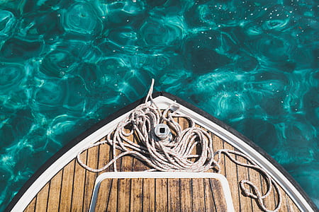 brown rope on brown wooden boat on blue water during daytime thumbnail