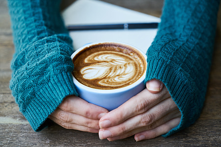woman wearing blue knitted long-sleeved shirt holding white ceramic teacup thumbnail