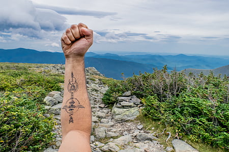 person raising arm with tiki totem tattoo thumbnail