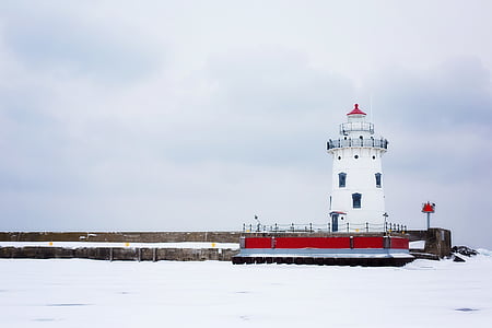 white and red lighthouse tower under white clouds daytime thumbnail