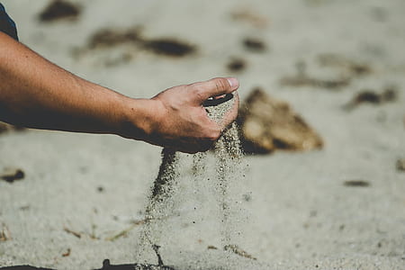 person scooping brown sand thumbnail