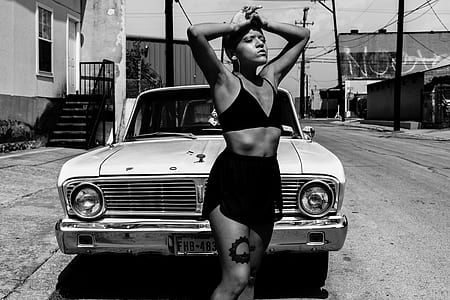 grayscale photography of white Ford car behind woman standing thumbnail