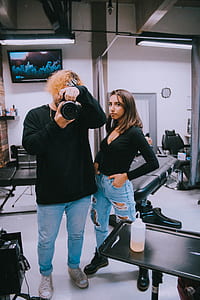 man holding camera while taking mirror picture beside woman inside the room thumbnail