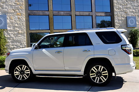 white Toyota 4Runner SUV parked beside concrete building at daytime thumbnail