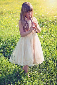 girl playing alto recorder while walking on green grass during daytime thumbnail