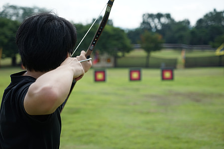 selective focus photo of person about to fire the arrow using bow during daytime thumbnail