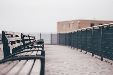 brown wooden bench near black metal fence on daytime thumbnail