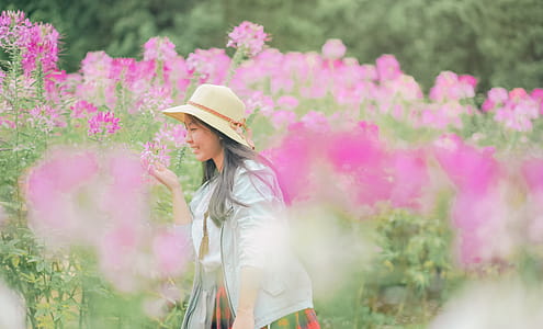 Woman Standing and Smelling Pink Petaled Flower thumbnail