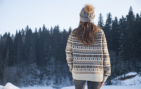 woman standing facing pine tree woods covered with snow thumbnail