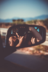 selective focus photography of car side mirror reflected the woman taking the picture using DSLR camera while inside the car thumbnail