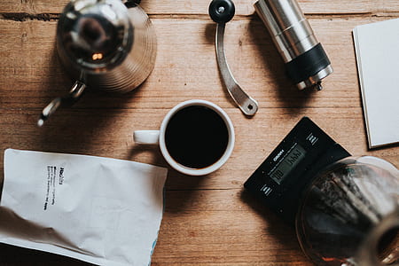 top view of white mug near black tube and gray tube on brown wooden surface thumbnail