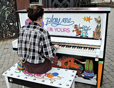 woman playing piano outside during daytime thumbnail