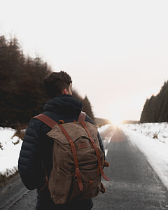 man carrying hiking backpack standing in the middle of road thumbnail